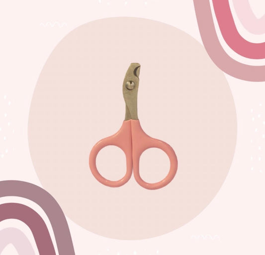 A pair of nail clippers with dusty pink handles and a metallic gold-toned head, centered on a soft pink background with abstract curved accents.